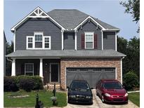 Charming two-story home with stone accents, a gray exterior, a well-maintained lawn, and an attached two-car garage at 3864 Lake Sanctuary Way, Atlanta, GA 30349