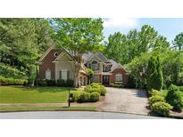 Charming two-story brick home with manicured lawn, mature trees, and inviting curb appeal at 1477 Edenham Ln, Cumming, GA 30041