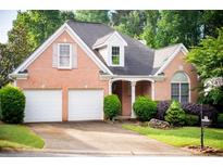 Charming brick home with a well-manicured lawn, mature trees, and a two-car garage at 3082 Monarch Pine Dr, Peachtree Corners, GA 30071