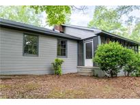 Charming home featuring a screened porch and gray siding, nestled among lush greenery for privacy at 147 Harris Loop, Dallas, GA 30157