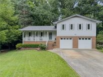 Charming home featuring a brick facade two-car garage, covered porch, and landscaped front yard at 5841 Covered Wagon Trl, Lilburn, GA 30047