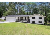 Charming renovated home with a freshly painted white brick exterior, black trim, and an inviting front porch at 106 Hickory Ave, Fayetteville, GA 30215