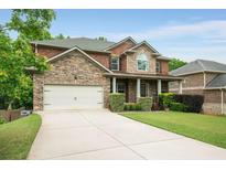 Beautiful two-story brick home with stone accents, manicured lawn, and a spacious driveway at 4415 Saint Andrews Crest Dr, Cumming, GA 30040