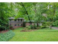 Beautiful two-story home with brick and siding, surrounded by lush trees and landscaping at 220 N Springs Ct, Sandy Springs, GA 30328