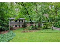 Charming home featuring a lush green lawn and mature trees for a private setting at 220 N Springs Ct, Sandy Springs, GA 30328