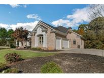 Charming brick home with a two-car garage, landscaped yard, and a well-maintained lawn on a sunny day at 6740 Mountain Lake Ln, Cumming, GA 30028