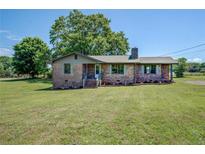 Charming brick home with a neatly manicured lawn and blooming flowerbeds, offering a warm and inviting curb appeal at 14721 Highway 36, Covington, GA 30014