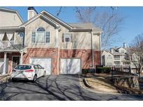 Two-story townhome featuring a two-car garage, brick accents, and well-maintained landscaping, providing a cozy curb appeal at 2114 Woodland Ln, Alpharetta, GA 30009