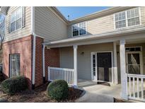 Inviting front entrance with neutral siding, brick accents, and a charming covered porch and dark front door at 2114 Woodland Ln, Alpharetta, GA 30009