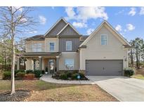 Two-story home featuring a well-manicured front yard, attached garage, and charming covered porch at 2496 Osceola Rd, Lithonia, GA 30058