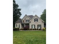 Charming two-story home with brick and stone exterior and well-manicured front lawn at 1640 Settindown Dr, Roswell, GA 30075