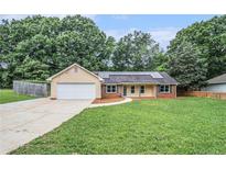 Charming single-story home with an attached garage, solar panels, and a well-maintained front lawn at 35 Riverbend Dr, Covington, GA 30014