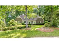 Charming two-story brick home with manicured landscaping and mature trees provides shade on a sunny day at 50 Stonington Pl, Marietta, GA 30068