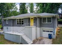 Charming home featuring a gray brick facade, a bright yellow front door and a well-maintained front yard at 2564 Riggs Dr, East Point, GA 30344