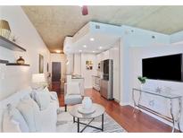 Open-concept living area with hardwood floors, modern furnishings, and stainless steel appliances at 855 Peachtree Ne St # 1311, Atlanta, GA 30308