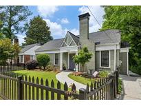 Charming brick home with a well-manicured lawn and a picket fence on a sunny day at 129 2Nd Se Ave, Atlanta, GA 30317