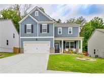 Charming two-story home featuring a well-manicured lawn, attached garage, and inviting front porch at 7730 Demeter Dr, Fairburn, GA 30213