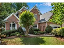 Beautiful brick home featuring a landscaped front yard, mature trees, and an attached garage at 2350 Shore View Nw Way, Suwanee, GA 30024