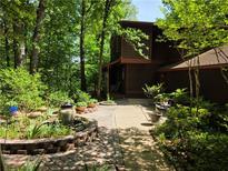 Landscaped pathway leading to a brown two-story home surrounded by lush trees at 406 Vivian Way, Woodstock, GA 30188