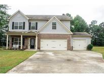 Charming two-story home with brick and siding exterior, a three-car garage, and a well-manicured front lawn at 1231 St James Pl, Loganville, GA 30052