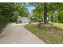 Charming single-story home with a long driveway and a screened in front porch surrounded by lush greenery at 1447 High Sierra Dr, Lawrenceville, GA 30043