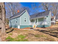 Charming two-story home with teal siding, a covered porch, and mature trees providing shade, creating an inviting curb appeal at 11 Pine St, Covington, GA 30014