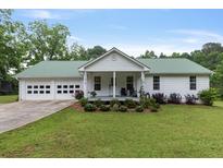 Charming home featuring a metal roof, two-car garage and a cozy front porch, surrounded by a well maintained lawn at 11415 Hutcheson Ferry Rd, Chattahoochee Hills, GA 30268