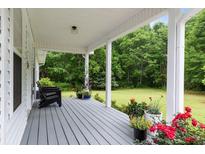 Inviting porch with gray floors, black chairs, and colorful flowers, perfect for relaxing outdoors at 11415 Hutcheson Ferry Rd, Chattahoochee Hills, GA 30268