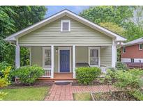 Charming bungalow with a covered front porch, blue door, and lush landscaping at 1265 Woodland Se Ave, Atlanta, GA 30316