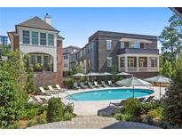 Upscale community pool with lounge chairs and umbrellas situated near brick and white trim buildings at 100 Sheridan Dr, Atlanta, GA 30305
