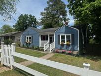 Charming blue home featuring a well-maintained yard, a white picket fence, and blooming flower boxes at 139 Merritt Se St, Marietta, GA 30060