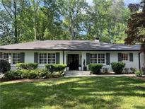Charming single-story home with classic white brick, black trim and shutters, complemented by a lush green lawn and mature trees at 1343 Peachtree Battle Nw Ave, Atlanta, GA 30327