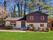 Charming home featuring a modern two-tone exterior with orange shutters, manicured lawn, and mature trees at 2814 Lloyd Rd, Decatur, GA 30034