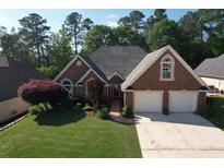 Charming brick home with a two-car garage, mature trees, and a well-manicured lawn at 940 River Valley Dr, Dacula, GA 30019