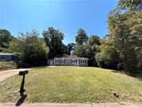 Charming single-story home featuring a well-manicured lawn and surrounded by mature trees at 1766 Venetian Sw Dr, Atlanta, GA 30311
