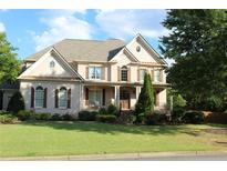 Charming two-story home featuring a brick facade, shuttered windows, and a well-manicured lawn at 100 Braxton Way, Roswell, GA 30075
