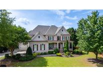 Stunning two-story home with lush landscaping, brick facade, covered porch and attached two-car garage at 100 Braxton Way, Roswell, GA 30075