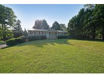 Charming single-story home with a well-manicured lawn, mature trees, and metal roof at 1003 Wiley Bridge Rd, Woodstock, GA 30188