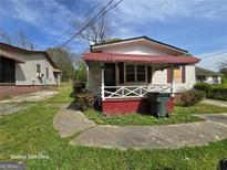 Exterior shot of home featuring a red and white color scheme, concrete driveway, and small front yard at 1243 Hill Nw St, Conyers, GA 30012