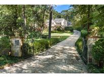 Long stone driveway leading to a beautiful home surrounded by mature trees and lush landscaping at 4375 Mount Paran Pkwy Nw, Atlanta, GA 30327