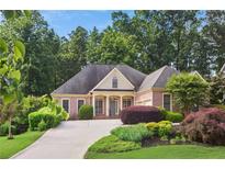 Charming brick home boasts a well-manicured front yard with lush landscaping and a welcoming driveway at 980 Ector Chase Nw, Kennesaw, GA 30152
