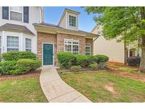 Charming townhome featuring stone accents, a well-manicured lawn, and a welcoming green front door at 1785 Fielding Way, Hampton, GA 30228
