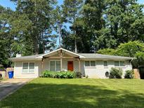 Charming brick home with a well-manicured lawn and a bright orange front door at 1909 Cindy Dr, Decatur, GA 30032