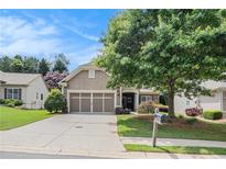 Charming home featuring a two-car garage, lush lawn, and mature landscaping at 4445 Vanadium Bend, Cumming, GA 30040