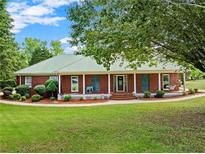 Charming brick home with a metal roof, welcoming front porch, and lush landscaping at 2620 Dr Bramblett Rd, Cumming, GA 30028