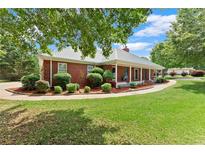 Charming single-story brick home with a metal roof, manicured lawn, and inviting front porch at 2620 Dr Bramblett Rd, Cumming, GA 30028