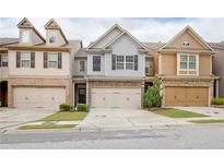Charming townhome featuring a two-car garage, stone accents, and manicured landscaping at 2243 Knoxhill Se Vw, Smyrna, GA 30082
