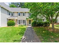 Charming two-story townhouse featuring a well-maintained lawn, mature trees, and neutral-toned siding at 4131 N Gloucester Pl, Atlanta, GA 30341
