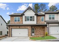 Beautiful two-story townhome featuring stone accents, white siding, and a two-car garage at 8210 Sonata Ln, Cumming, GA 30041