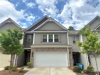 Charming townhome with a two-car garage, manicured lawn, and gray brick and siding at 2264 Shetley Creek Dr, Norcross, GA 30071